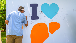 Man signs the Liver Health Pledge wall